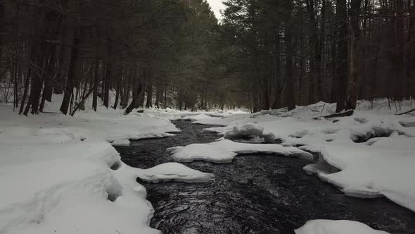 Drone shot going down snowy river in winter