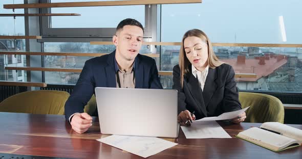 Man and a Woman Discussing Work in the Brightly Lit Modern Office. Concerned Male and Female Working