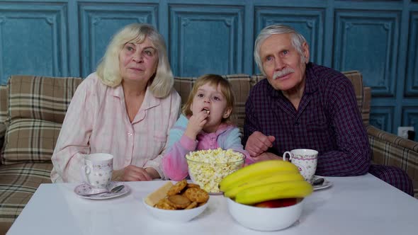 Family Grandparents Getting Scared Watching Horror TV Television Movie with Granddaughter at Home