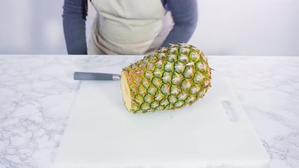 Step by step. Cutting pineapple on a white cutting board.