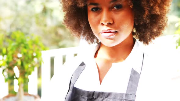 Portrait of smiling waitress standing with arm crossed