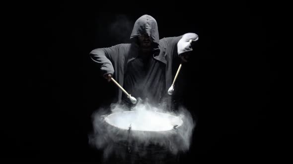 Hooded Man Beats Drum with Flour