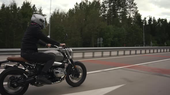 Man Riding Scrambler Motorbike on the Highway Through the Autumn Forest