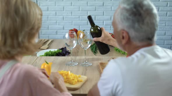 Romantic Man Pouring Red Wine in Glasses, Happy Couple Cooking Together at Home