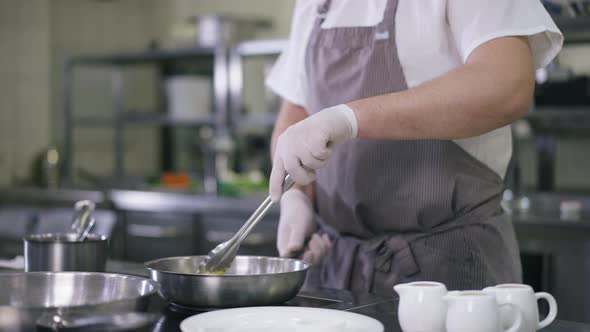 Unrecognizable Cook in Apron Turning Pineapple Frying Fruit Slice on Cooking Pan in Commercial