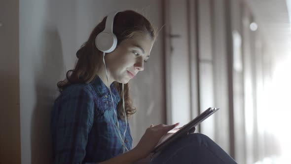 Young Woman with Tablet Sitting in Hallway