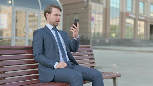 Upset Businessman Reacting to Loss on Smartphone Outdoor