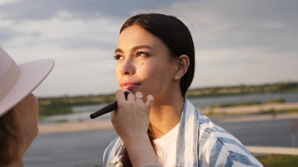 Visagiste Helping Beautiful Model To Put on Make Up.