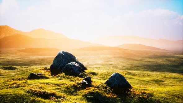 Meadow with Huge Stones Among the Grass on the Hillside at Sunset