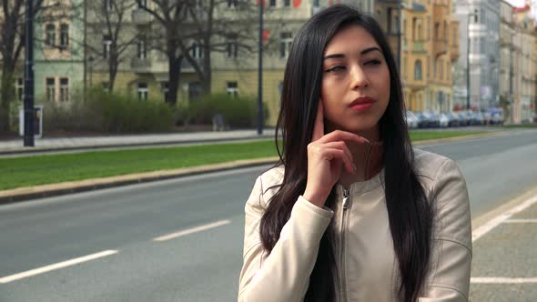 A Young Asian Woman Broods Over Something in a Street in an Urban Area