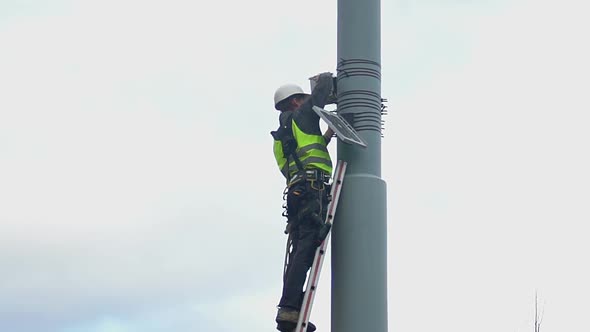 Municipal Engineer Standing on Ladder at Height, Hazardous Maintenance Work