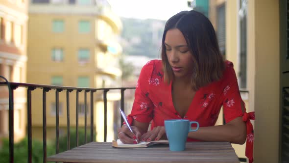 A woman writing in a journal diary traveling in a luxury resort town in Italy, Europe