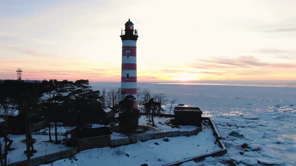 Bright Sun Illuminates Lighthouse Surrounded By Frozen Sea