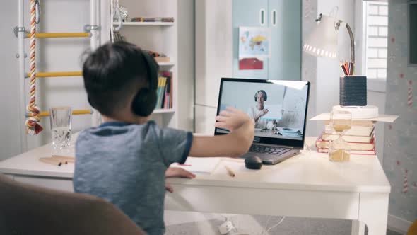 Little Schoolkid Waving To His Teacher During an Online Class