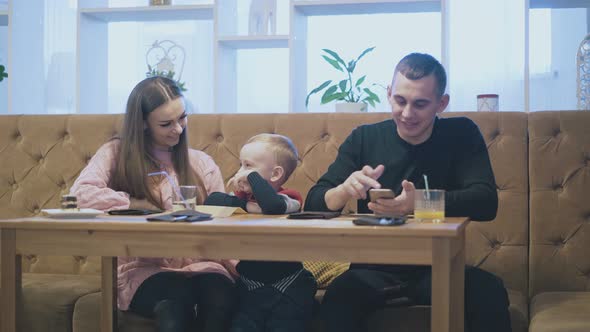 Happy Man Sends Message on Smartphone and Wife Kisses Child