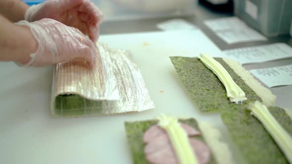 Cook Prepares a Japanese Roll Wraps Rice Outside Using a Mat