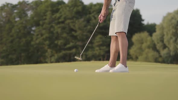 Unrecognized Man Playing Golf on the Golf Field. Confident Man Warming Up and Hitting the Ball Using