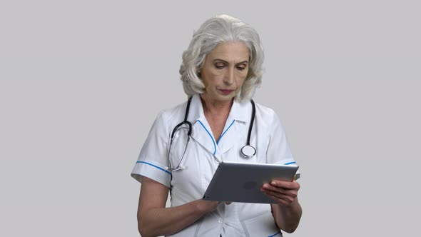 Serious Pensive Senior Female Doctor Using Tablet Pc Device