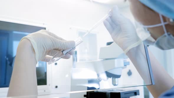 Scientist with a Pipette Analyzes a Colored Liquid To Extract the DNA and Molecules in the Test