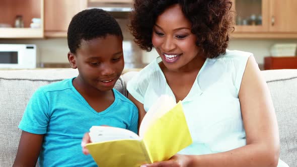 Mother and son reading a book in living room 4k