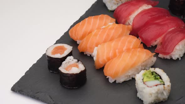 Sushi typical Japanese Asian food. Nigiri salmon, tuna, hosomaki, uramaki rotating on a plate in whi
