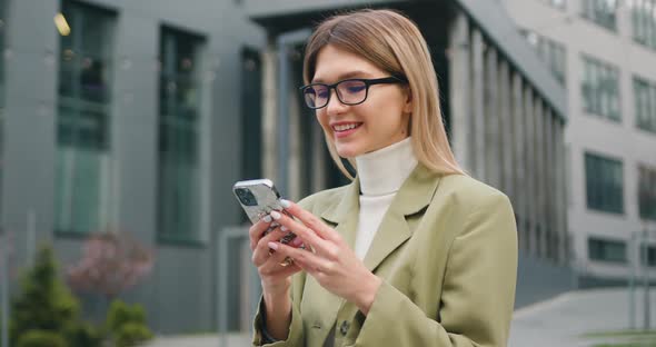 Beautiful Businesswoman Wearing Smart Casual Clothes Using Smartphone on Urban Street.