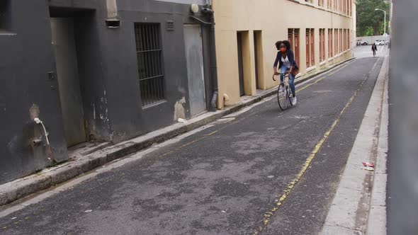 African american woman wearing face mask riding bicycle in street