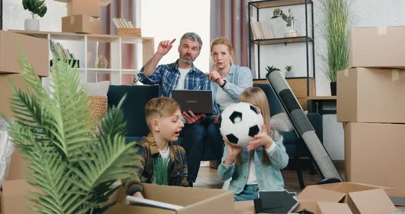 Couple Sitting on the Couch and Discussing Design of their New Apartment Using Computer