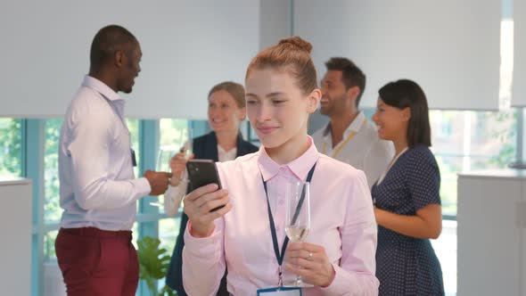 Dolly Push Shot of Young Businesswoman at Office Party Reading Important Email on Smartphone