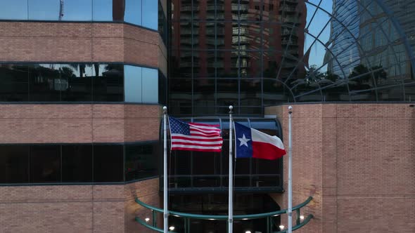 Texas and USA flags at office building in downtown. Rising aerial reveal of business and state gover