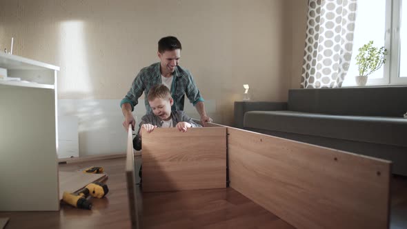 Happy Father and Son are Trying to Fix the Walls of the Cabinet with a Shelf