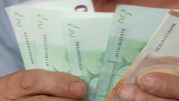 Close-up of euro banknotes in the hands of an elderly man.