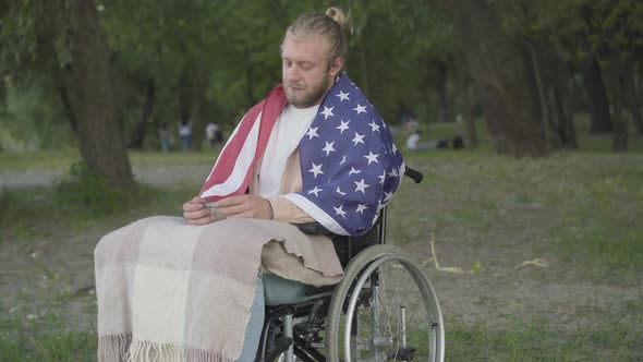 Portrait of Sad Paraplegic Veteran on Wheelchair Looking at Military Stripe and Smiling. Camera