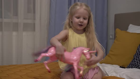 A Beautiful Child of 5 Years Old Plays with a Pink Unicorn