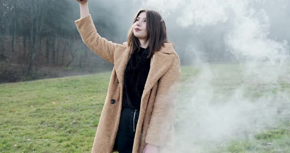 Woman Makes Emergency Flare Signal with White Smoke. Hipster Pretty Girl with Smoke Bomb