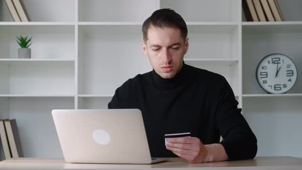 Young Male Businessman Holding Credit Card and Using Laptop While Paying for Order in Web Store