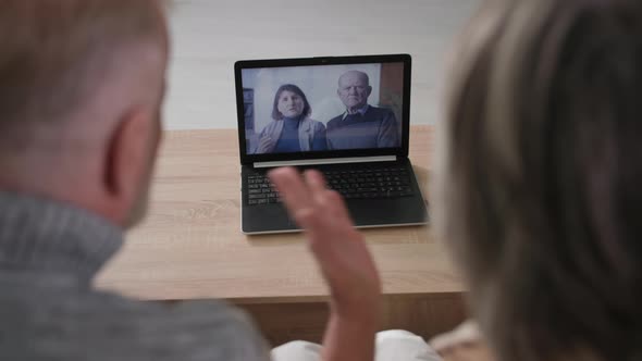 Grayhaired Married Couple Chatting with Elderly Friends Using Laptop Mature Man and Woman Looking at