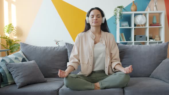 Slow Motion of Happy Girl in Headphones Listening To Music and Relaxing in Lotus Position