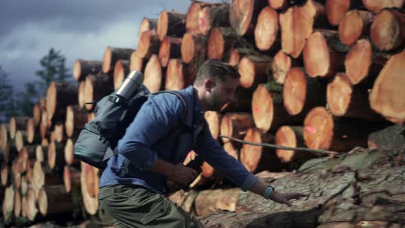 Hiker walking on tree trunk at stack of wood