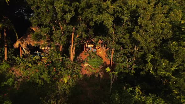 Young man sitting at a table on his patio deep within a hillside rainforest. Aerial footage of backw
