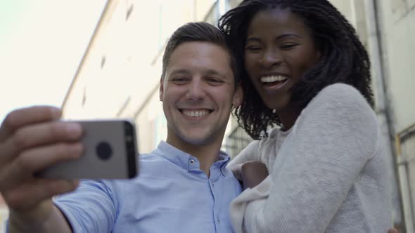 Cheerful Interracial Couple of Tourists Posing for Selfie