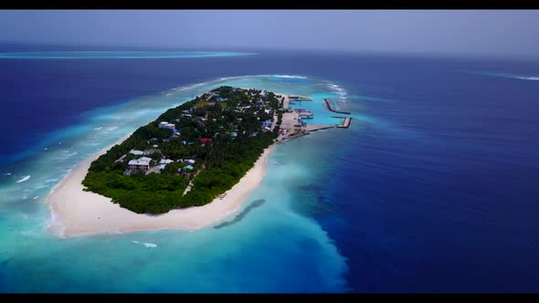 Aerial panorama of tranquil tourist beach wildlife by blue ocean and white sandy background of journ