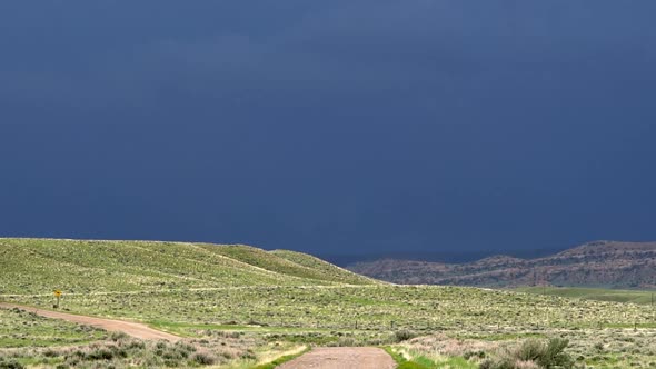 Lightning flashes in dark stormy clouds across green landscape