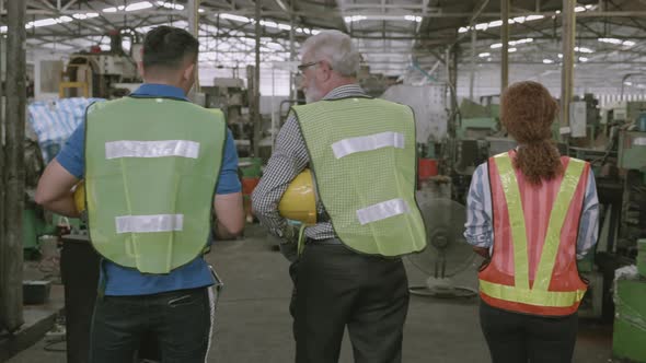 Team engineer in hard hat walking and talking with professional in industrial factory.