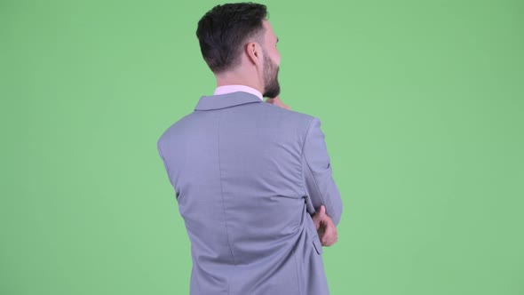 Rear View of Young Bearded Businessman Thinking and Looking Around