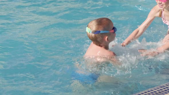Little Boy and Girl Swimming in Swimming Pool Children Having Fun Splashing Water