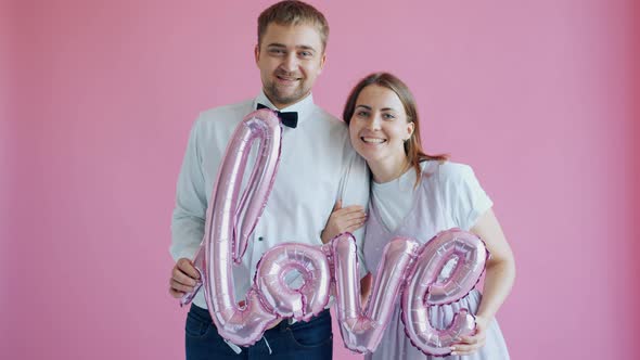 Loving Couple Holding Word Love on Pink Background Feeling Happy Connected