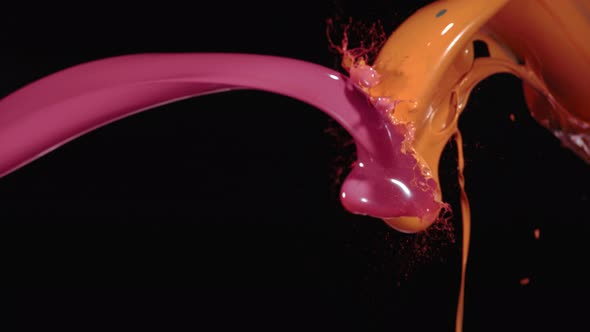 Pink and orange paint splash mixing against black background. Slow Motion. alt