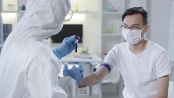 Doctor in Protective Gear Discussing Blood Sample with Patient