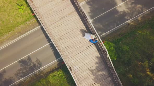 Newly Wedded Couple at Railing on Wooden Bridge Aerial View